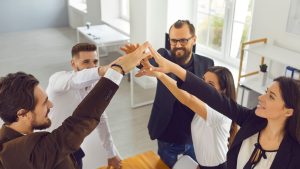 a group of people in an office giving each other high fives - Real Estate Sales LLC